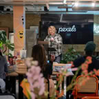 A woman leading a workshop in a stylish office setting, engaging with a small audience.