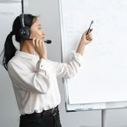Asian woman presenting ideas on a whiteboard in a corporate office.